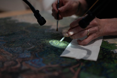 Restaurator Kathrin Pilz verwijdert de vernislaag van Olijfgaard met fijn gereedschap onder de microscoop. Foto: Isabell Janssen