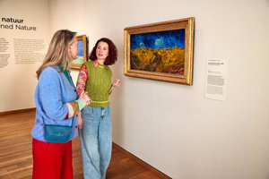 Twee vrouwen praten met elkaar bij het schilderij Korenveld met Kraaien van Vincent van Gogh in het Van Gogh Museum. Foto Suzanne Karsters