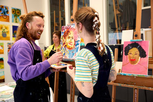 Een man schildert zijn zelfportret in het atelier van het Van Gogh Museum en kijkt lachend naar de workshopdocente. Foto: Suzanne Karsters