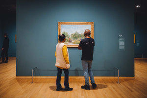 Twee bezoekers kijken naar het schilderij Tuin met geliefden: Square Saint-Pierre van Vincent van Gogh. Foto: JD Photography