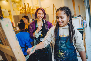 Meisje en workshopdocent hebben plezier tijdens een schilderworkshop. foto: Jelle Draper