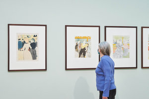 In the exhibition Here to Stay, a woman is looking at the print The Female Clown at the Moulin Rouge by Toulouse-Lautrec. Photo: Tomek Dersu Aaron