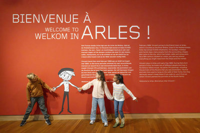 Three children pretend to shake hands with an illustrated version of Camille Roulin in the exhibition Van Gogh and the Roulins at the Van Gogh Museum. Photo: Anke van der Meer