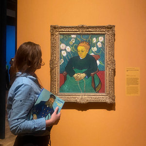 Woman holding the exhibition catalogue in front of Van Gogh's 'La Berceuse'