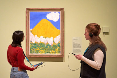 Museumbezoekers in de tentoonstelling 'Geel. Meer dan Van Goghs lievelingskleur' bij het schilderij 'De gele heuvel' van Cuno Amiet. , foto: Michael Floor