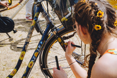 A girl with sunflowers in her hair is drawing sunflowers on her bike at the Sunflower Art Festival to celebrate the Van Gogh Museum's 50th anniversary on 2 June 2023. Photo: David Stegenga / Jelle Draper