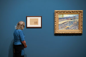 In the exhibition, a woman compares Vincent van Gogh's letter sketch with the painting Field with a Plowman from 1889. Photo: Tomek Dersu Aaron