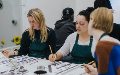 Drie jonge vrouwen zijn met inkt aan het tekenen tijdens een worskshop in het Van Gogh Museum. Foto: Alicia Karsonopoero