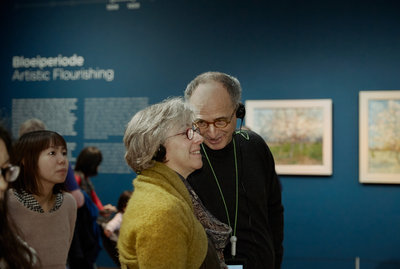 Een ouder echtpaar met multimediatour fluistert elkaar iets toe in het museum. Foto: Maaike Koning