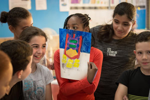 Een meisje laat het resultaat zien van haar schilderworkshop