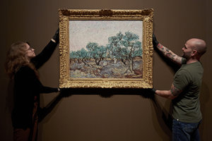 Two museum employees are handling an artwork in the exhibition 'Van Gogh and the Olive Groves'. Van Gogh Museum, Amsterdam (Photo: Michael Floor)