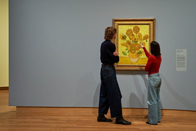 Two visitors to the exhibition Yellow. Beyond Van Gogh's Colour are looking at Vincent van Gogh's painting Sunflowers. Photo Michael Floor
