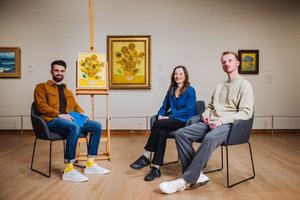 Nienke Bakker en Stijn Oom worden geïnterviewd over de LEGO Sunflowers set in he Van Gogh Museum met op de achtergrond het schilderij Zonnebloemen van Vincent van Gogh