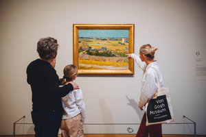Een gezin krijgt een rondleiding in het Van Gogh Museum bij het schilderij De oogst van Vincent van Gogh. Foto: Jelle dRaper