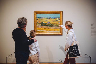 Een gezin krijgt een rondleiding in het Van Gogh Museum bij het schilderij De oogst van Vincent van Gogh. Foto: Jelle dRaper