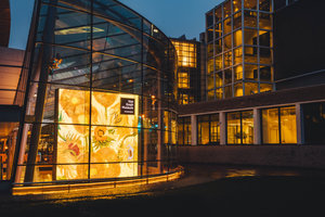 De verlichte glazen hoofdingang van het Van Gogh Museum in de avond. Foto: Jelle Draper