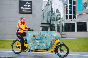 DHL pakketbezorger met haar bakfiets op het Museumplein voor het Van Gogh Museum. Foto: Jelle draper