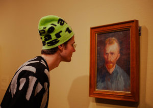 A young person is looking at a self-portrait by Vincent van Gogh at the Van Gogh Museum.