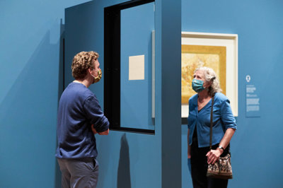 Two visitors wearing face masks look at the front and back of a letter in the exhibition. Photo: Tomek Aaron Dersu