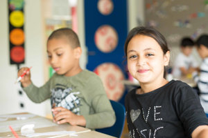  A boy and a girl are drawing in the classroom at a primary school. The girl is smiling and looking into the camera. Photo: Brenda Roos
