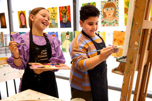 Een meisje kijkt lachend naar het schilderij dat de jongen naast haar heeft gemaakt in de kinderworkshop van het Van Gogh Museum. foto: Suzanne Karsters