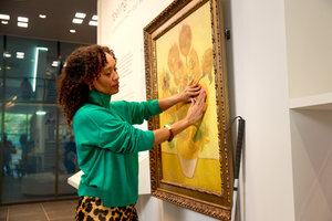 Een vrouw voelt de verfstreken op een 3d-reproductie van Van Goghs schilderij Zonnebloemen in het Van Gogh Museum. Foto: Suzanne Karsters