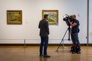 Een tv-presentator wordt gefilmd voor twee schilderijen van Vincent van Gogh: De brug van Langlois en Korenveld. Foto: Jan-Kees Steenman